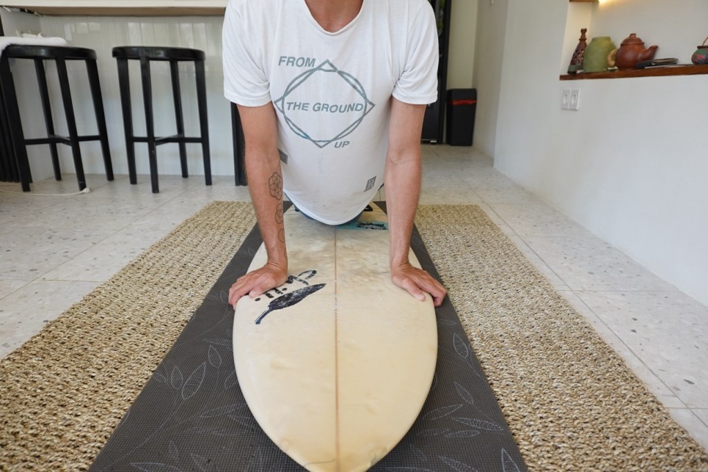 Holding onto rails of surfboard